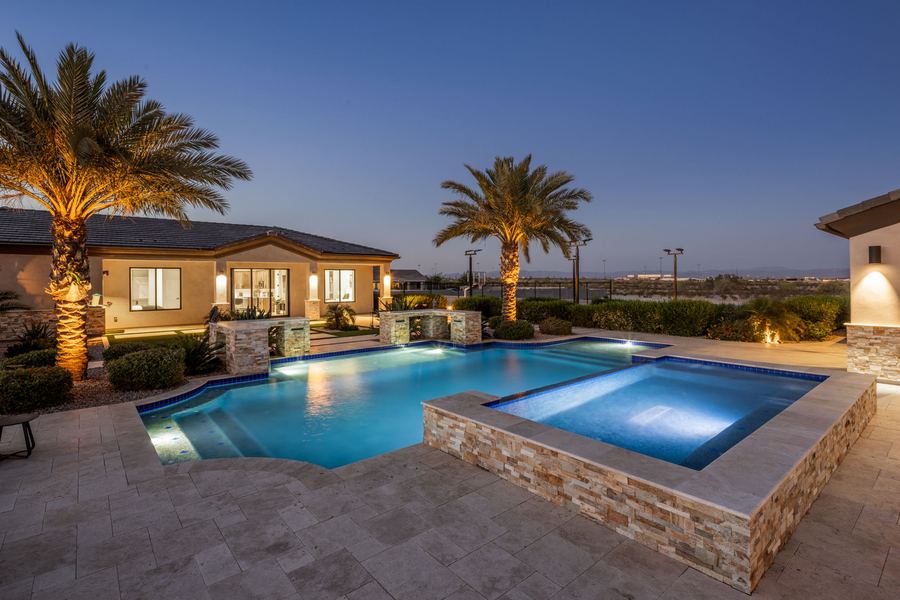 Lit spa with stacked stone wall beside the pool at blue hour