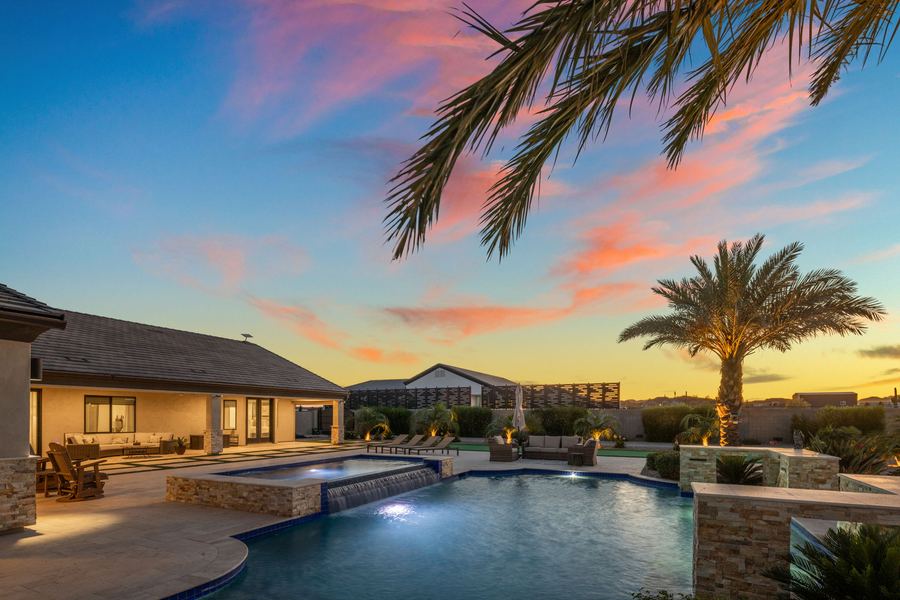 Curving pool and spa spillover at sunset under palm fronds