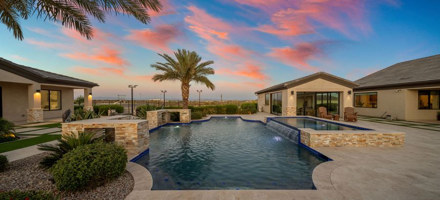 Pool and stone water features toward the pool house at sunset