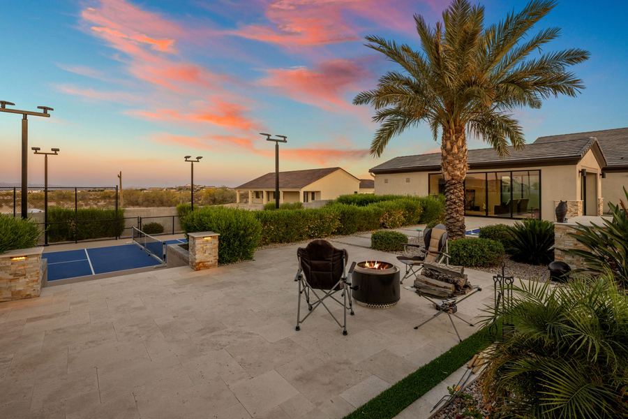 Fire pit seating on the travertine terrace beside the court at sunset