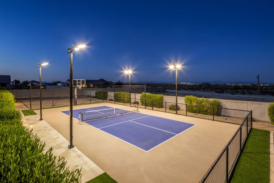 Lit pickleball court with fencing and turf edges at blue hour