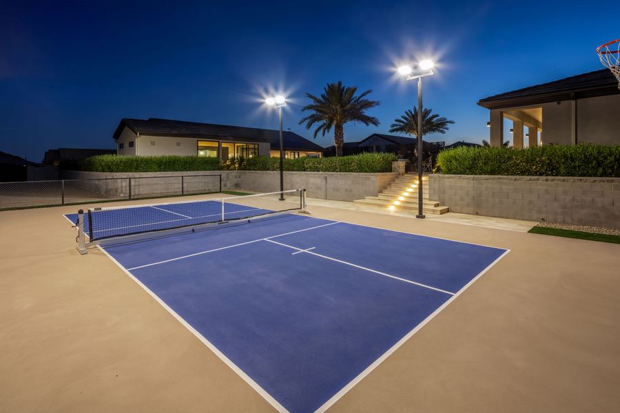 Lit pickleball court with steps up to the pool terrace at night