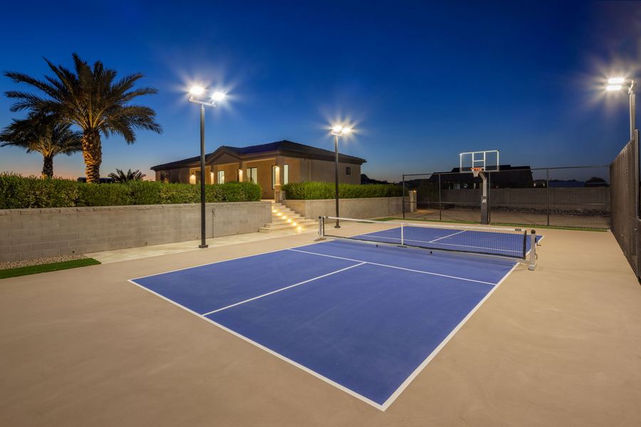 Pickleball court under lights below the palms and main house at night