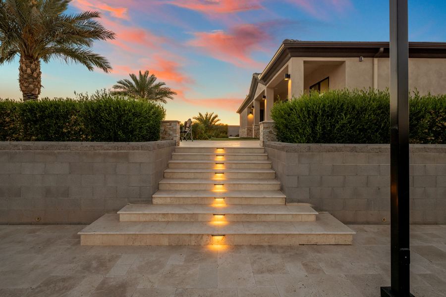 Lit travertine steps between block walls rising from the court