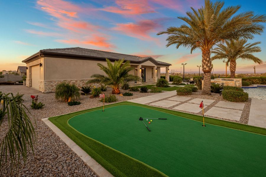 Putting green with clubs and balls beside the pool house at sunset