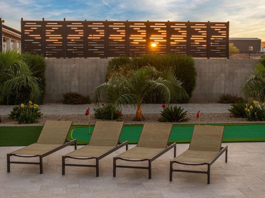 Row of loungers on travertine before a slatted privacy screen at sunset