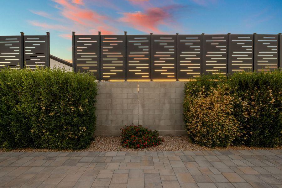 Hedges and a slatted privacy screen above a paver walk at sunset