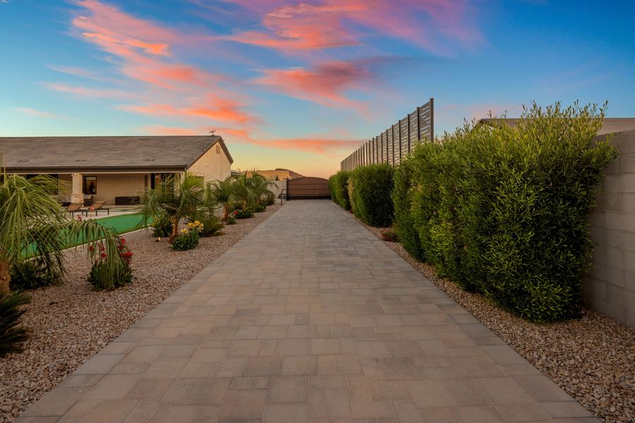 Paver side walk between hedges and plantings at sunset