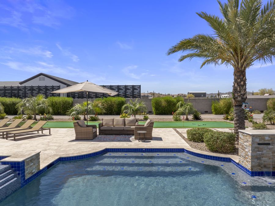 Pool edge with lounge terrace, umbrella and putting green beyond