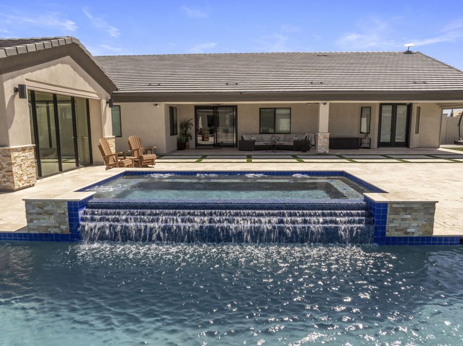 Raised spa spilling into the pool in front of the covered patio