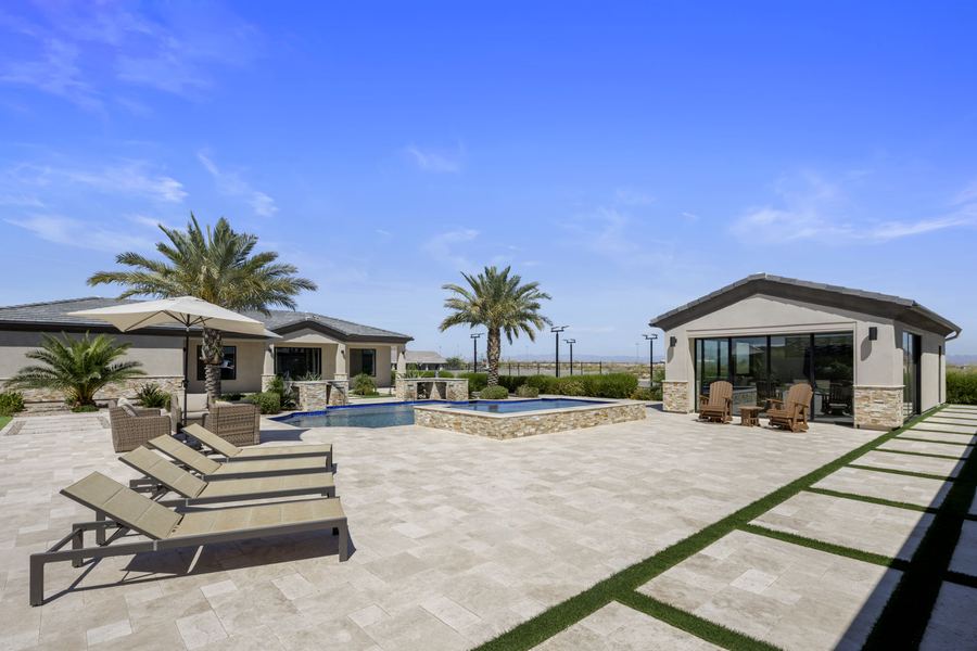 Loungers on the travertine deck near the pool and pool house