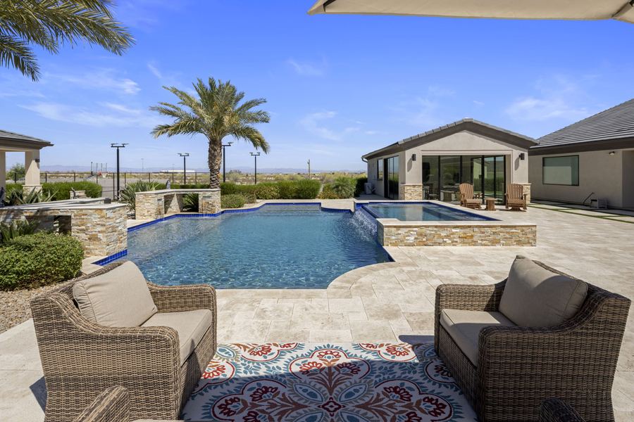 Wicker lounge chairs on a rug overlooking the pool