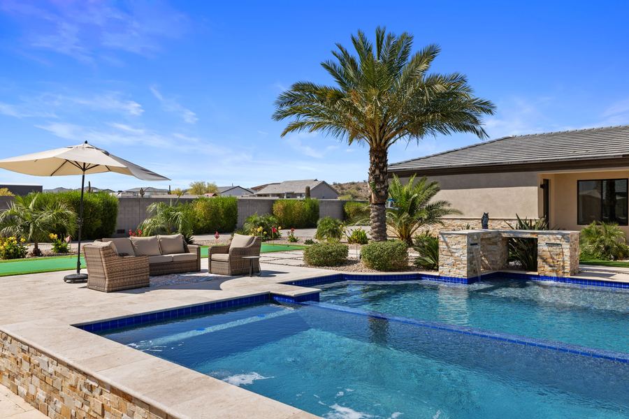 Outdoor sofa set and umbrella beside the pool with a palm