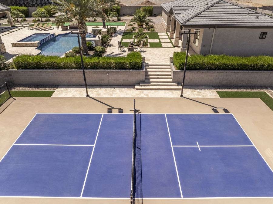 Pickleball court below steps up to the pool and yard