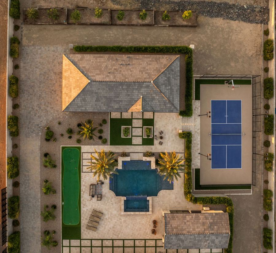 Top-down twilight view of the backyard, pool, putting green and court