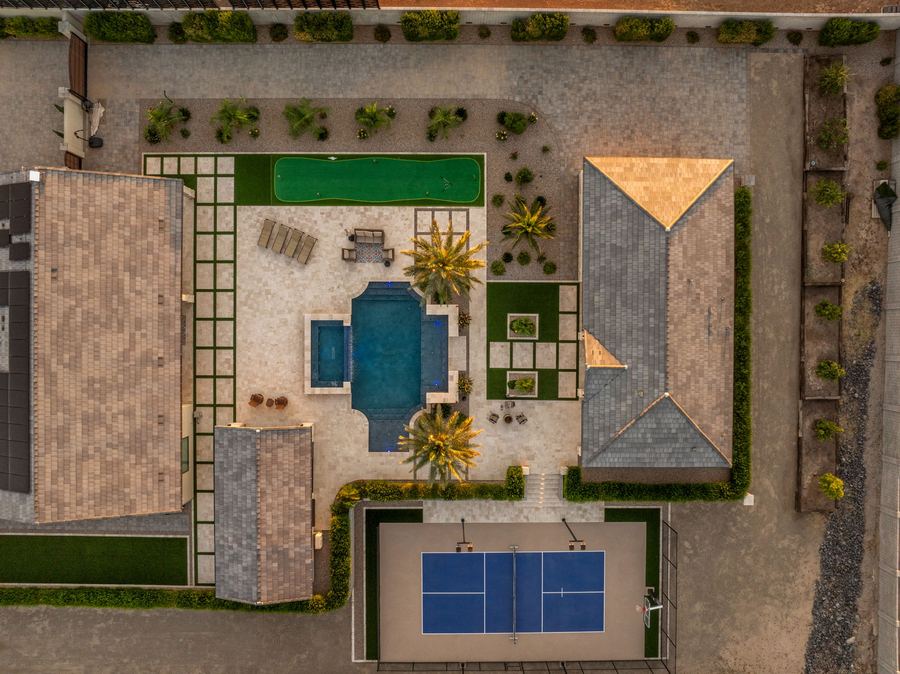 Top-down twilight view of the turf grid, pool, palms and court