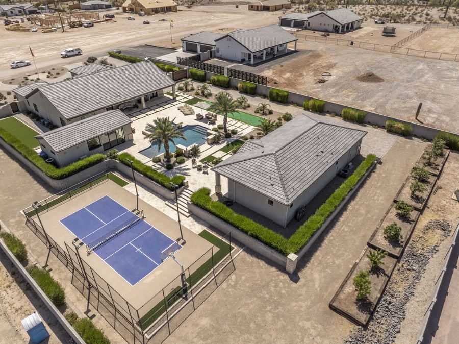 Aerial view of the full backyard with pool, court and pool house