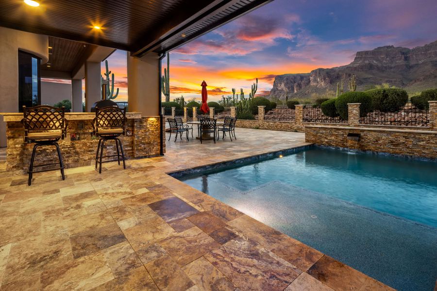 Bar seating beside the pool under a mountain sunset