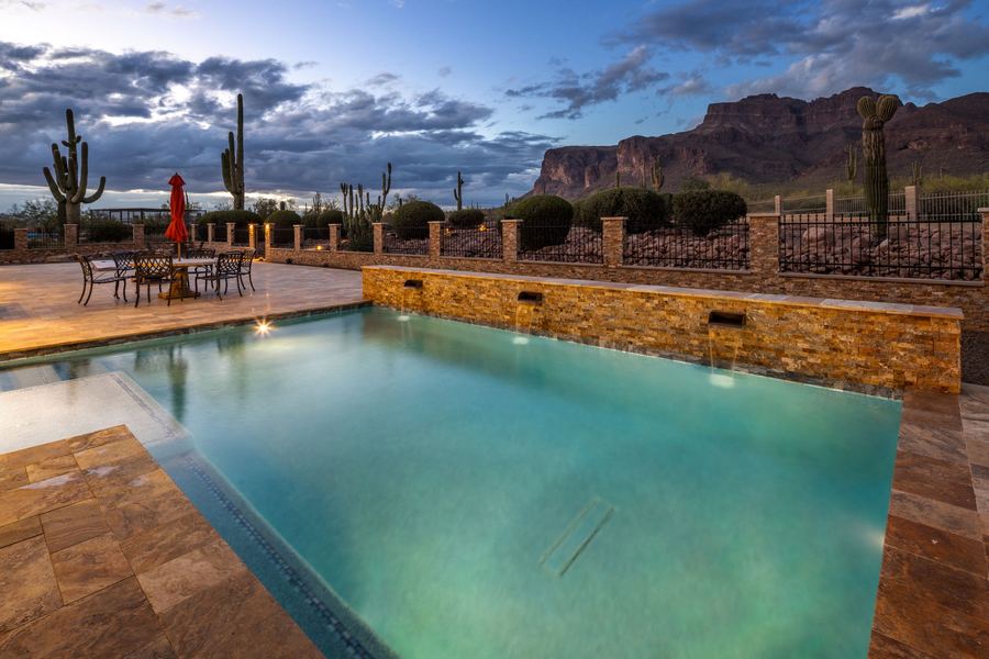Rectangular pool at blue hour with stacked stone wall and mountains beyond