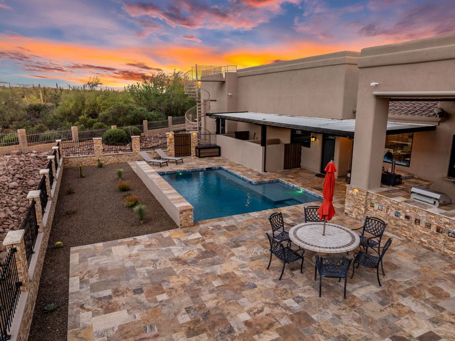 Low aerial at sunset over travertine patio, dining table and pool