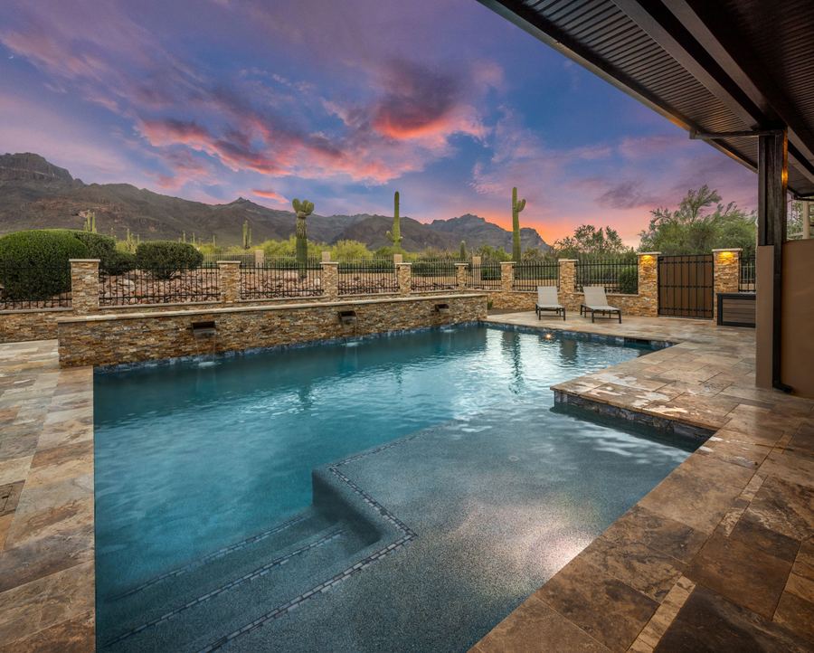 Pool and tanning ledge viewed from the covered patio at dusk