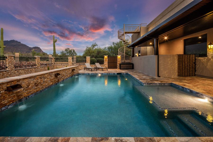 Lit pool looking back toward the house and covered patio at twilight