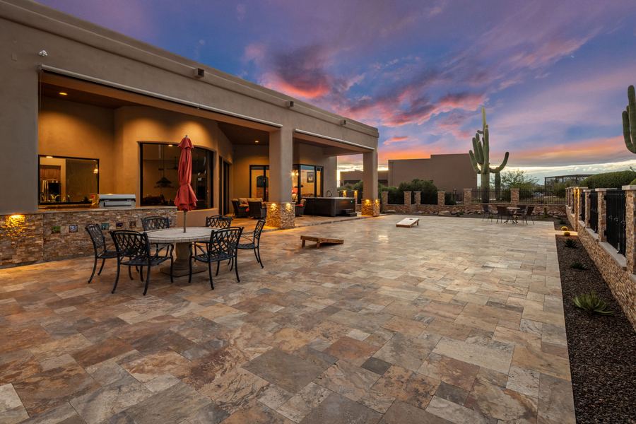 Dining set on travertine patio beside the house at sunset