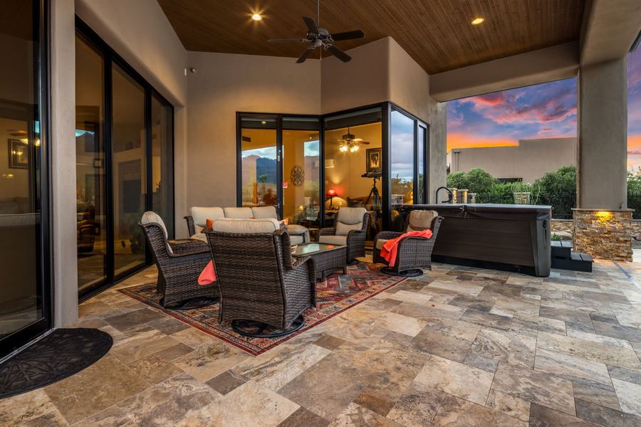 Covered patio lounge with wicker seating and hot tub at sunset