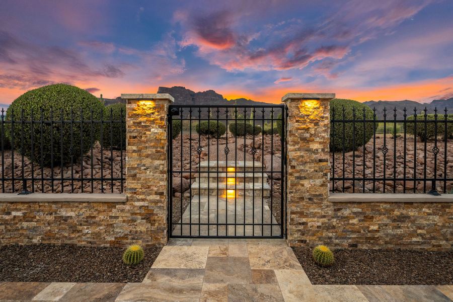 Iron gate between lit stacked stone pillars at sunset