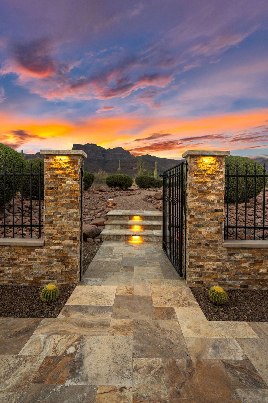 Lit travertine steps through a stone pillared gate at dusk