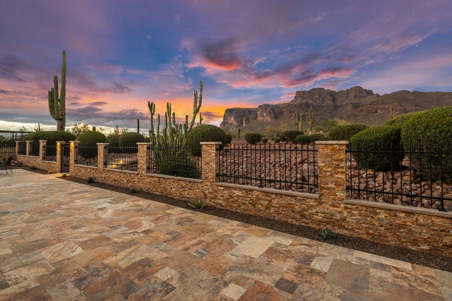 Stacked stone wall with iron panels framing a sunset mountain view