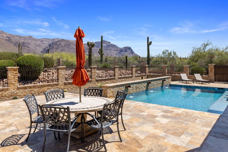 Dining table with red umbrella beside the pool on a sunny day