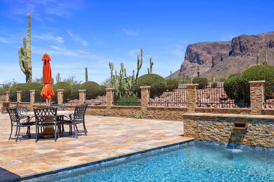 Pool with sheer water features and dining area by day