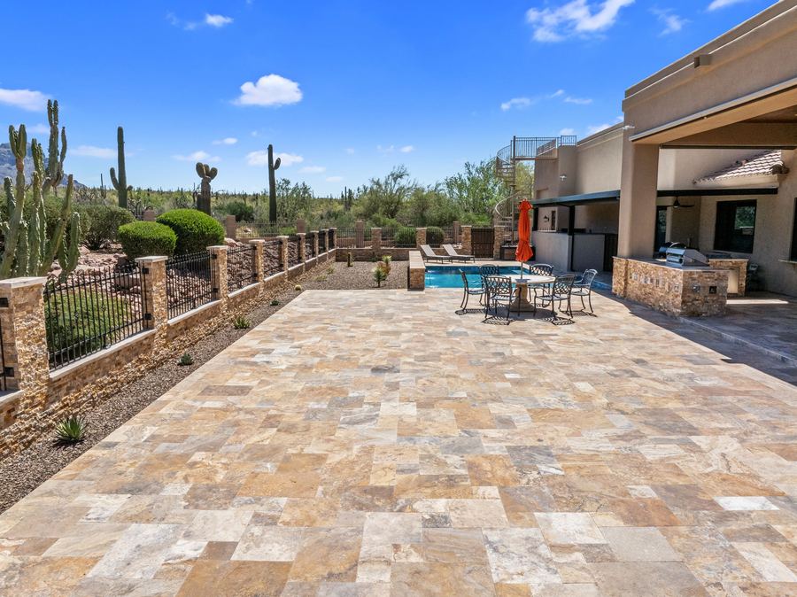 Wide travertine patio leading to the pool and covered patio