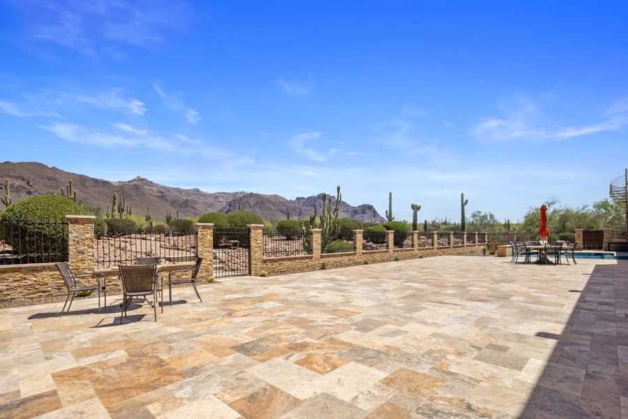 Open travertine patio along a stone and iron perimeter wall