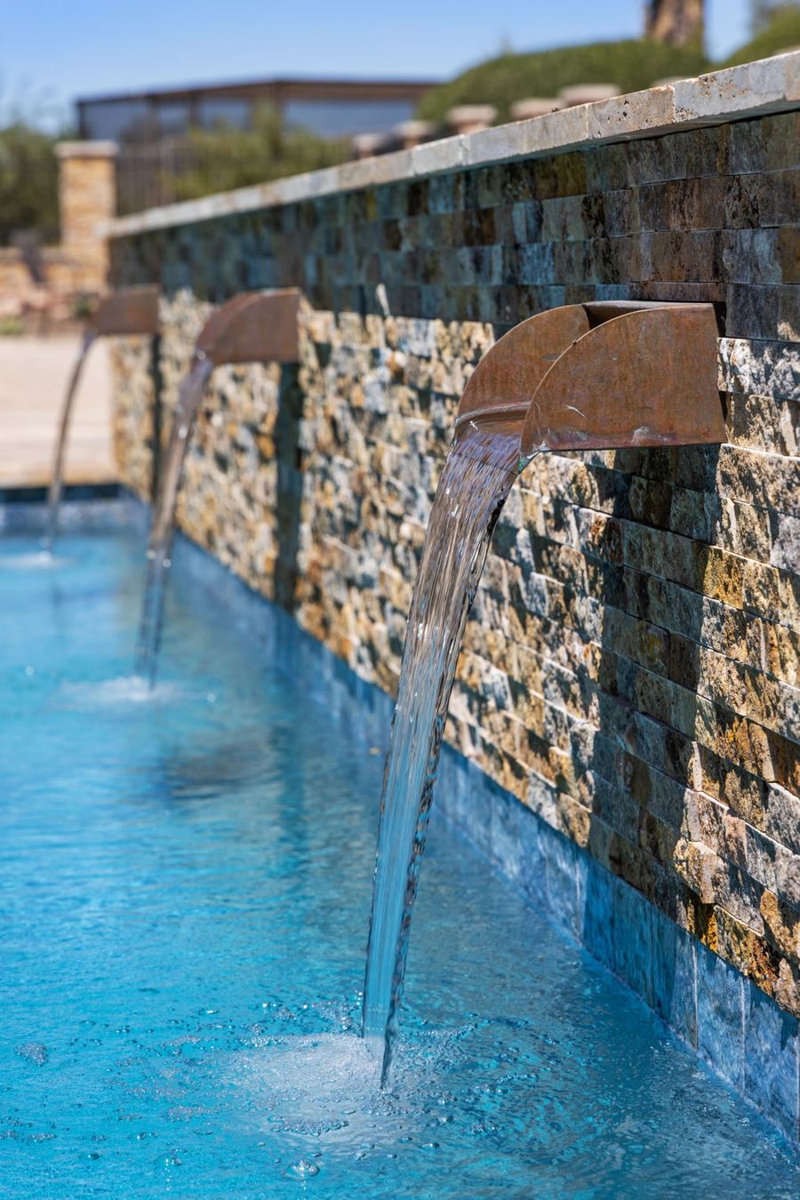 Close view of a bronze scupper pouring into the pool