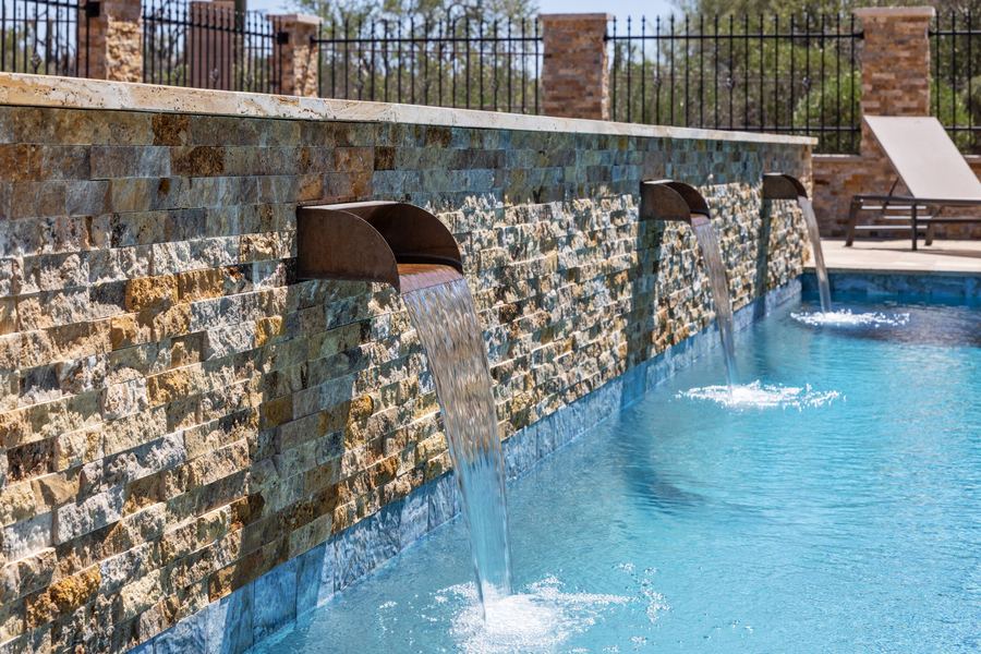 Three sheer water features flowing from a stacked stone wall