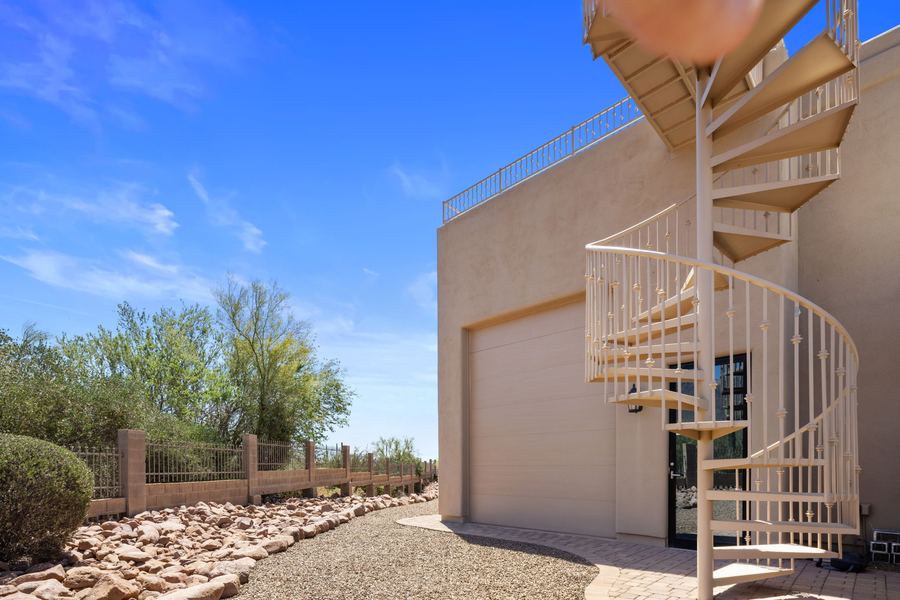 Spiral staircase to a rooftop deck above desert landscaping