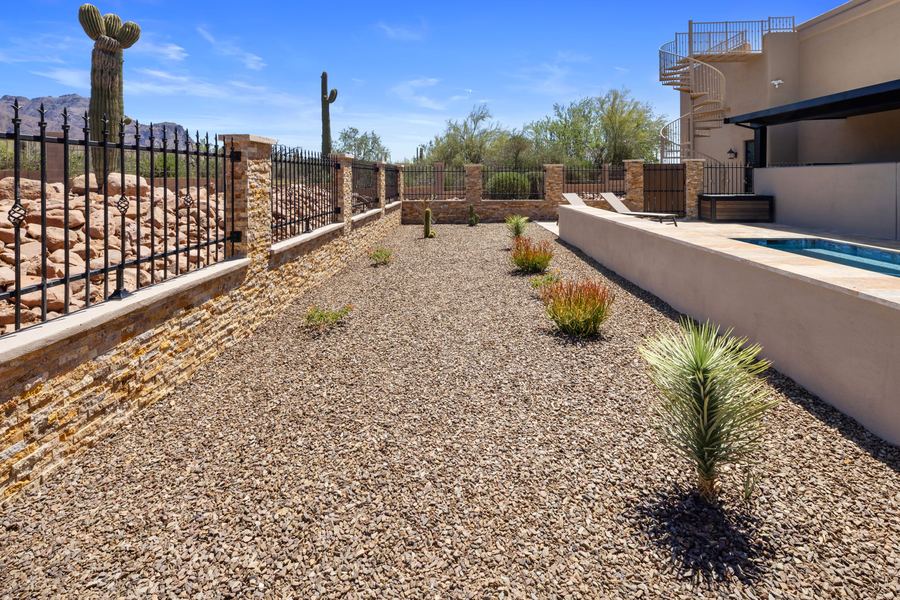 Gravel side yard with desert plants beside the stone clad pool wall