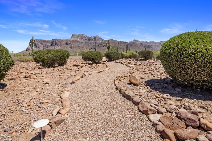 Rock edged gravel path through desert landscaping toward mountains