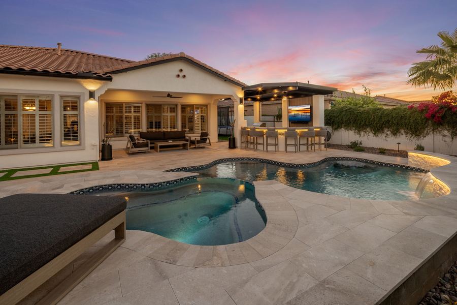 Freeform pool facing the covered patio and outdoor bar at twilight