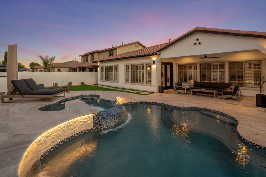 Lit stacked stone pool wall and freeform pool at twilight