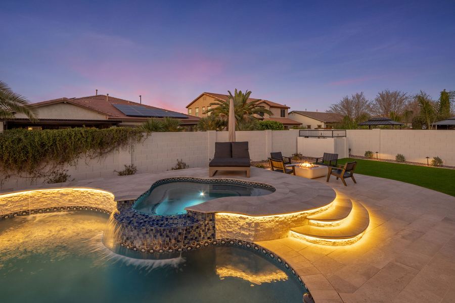 Raised tiled spa spilling into the pool beside lit curved steps
