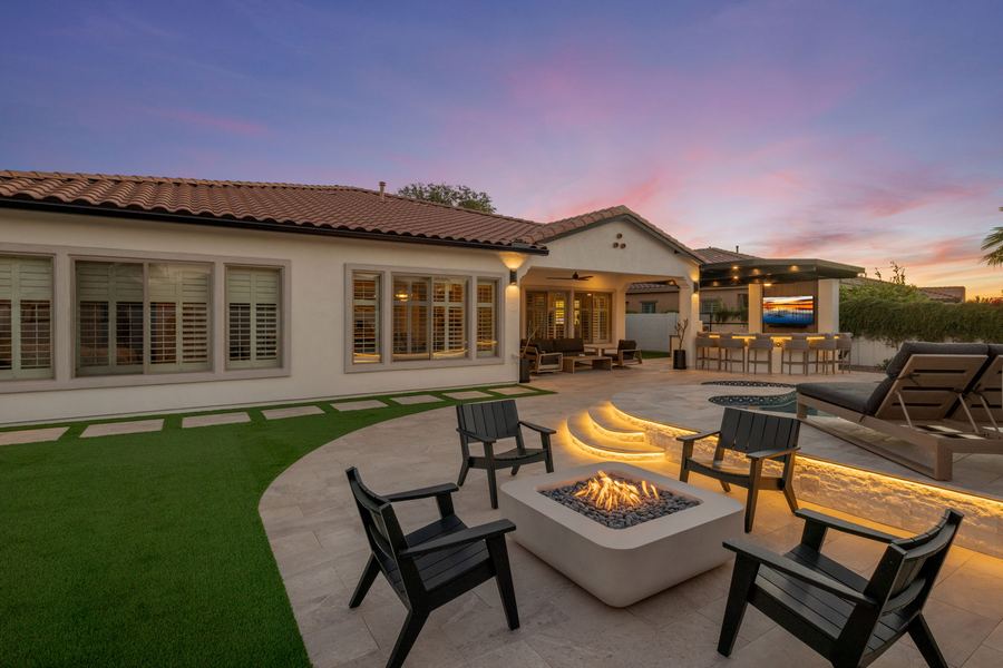Square fire pit with lounge chairs on the patio at twilight