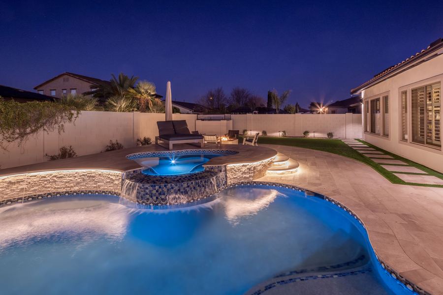 Raised spa with spillover and lit pool at night