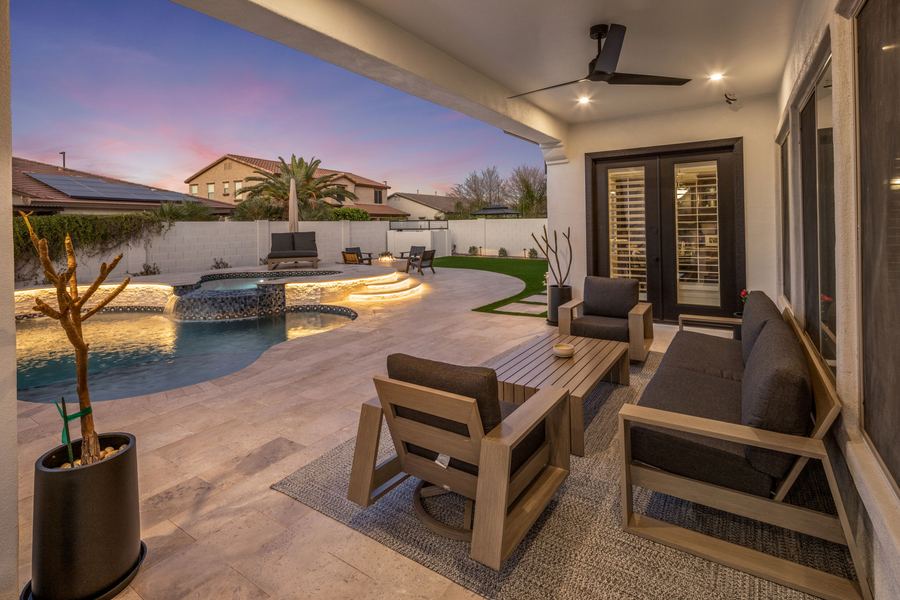 Covered patio seating looking out over the lit pool and spa
