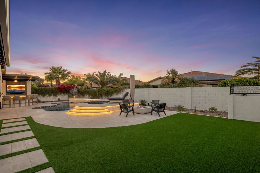 Turf lawn with stepping pavers leading to the pool and fire pit