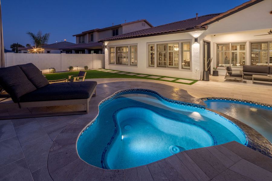Lit spa with a daybed lounger and home at night