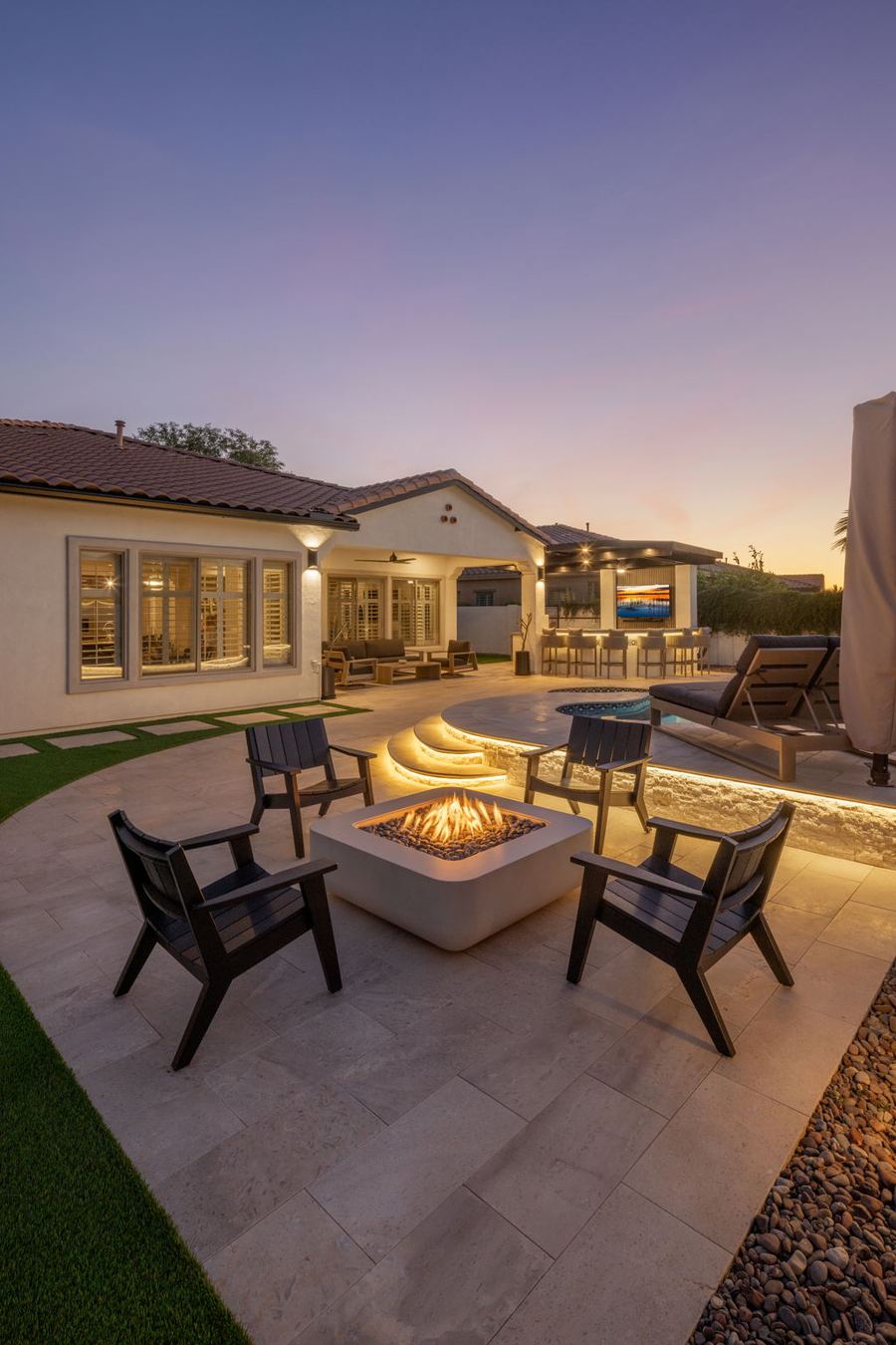 Fire pit seating on the patio with lit pool steps behind