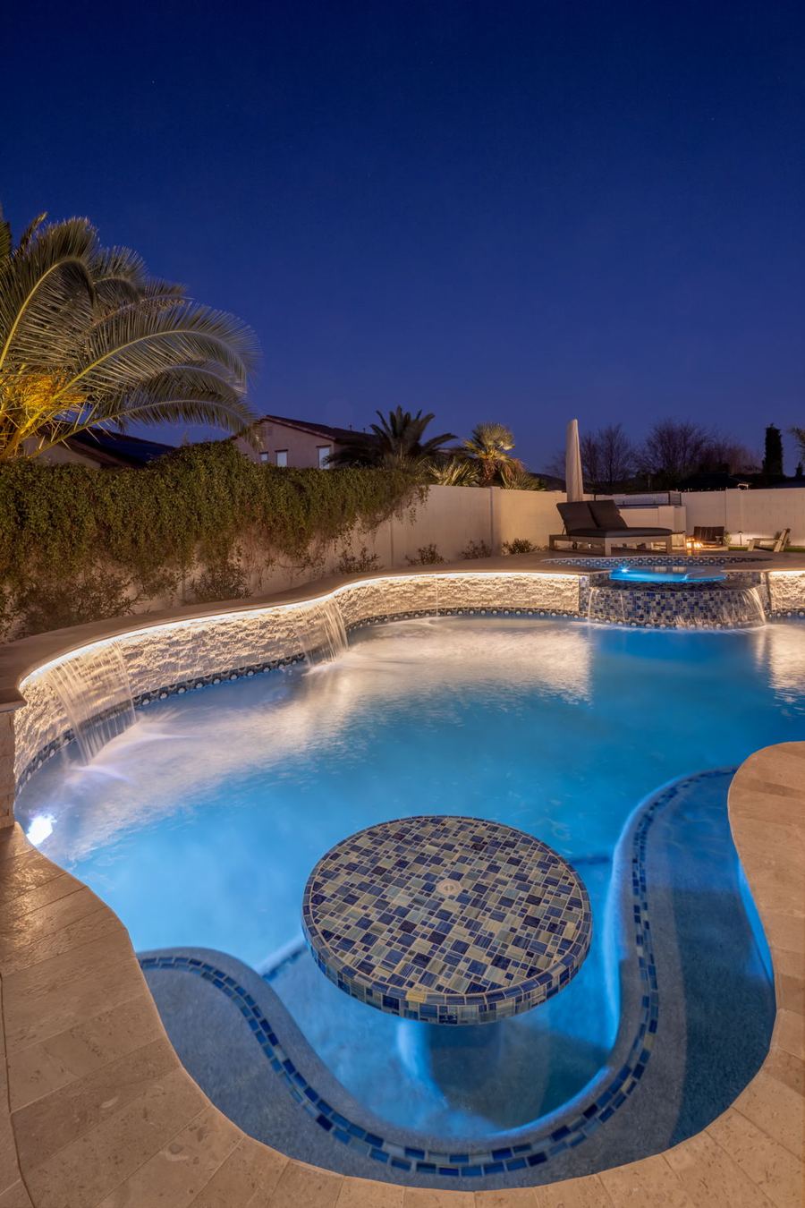 Tiled table in the lit pool lagoon at night